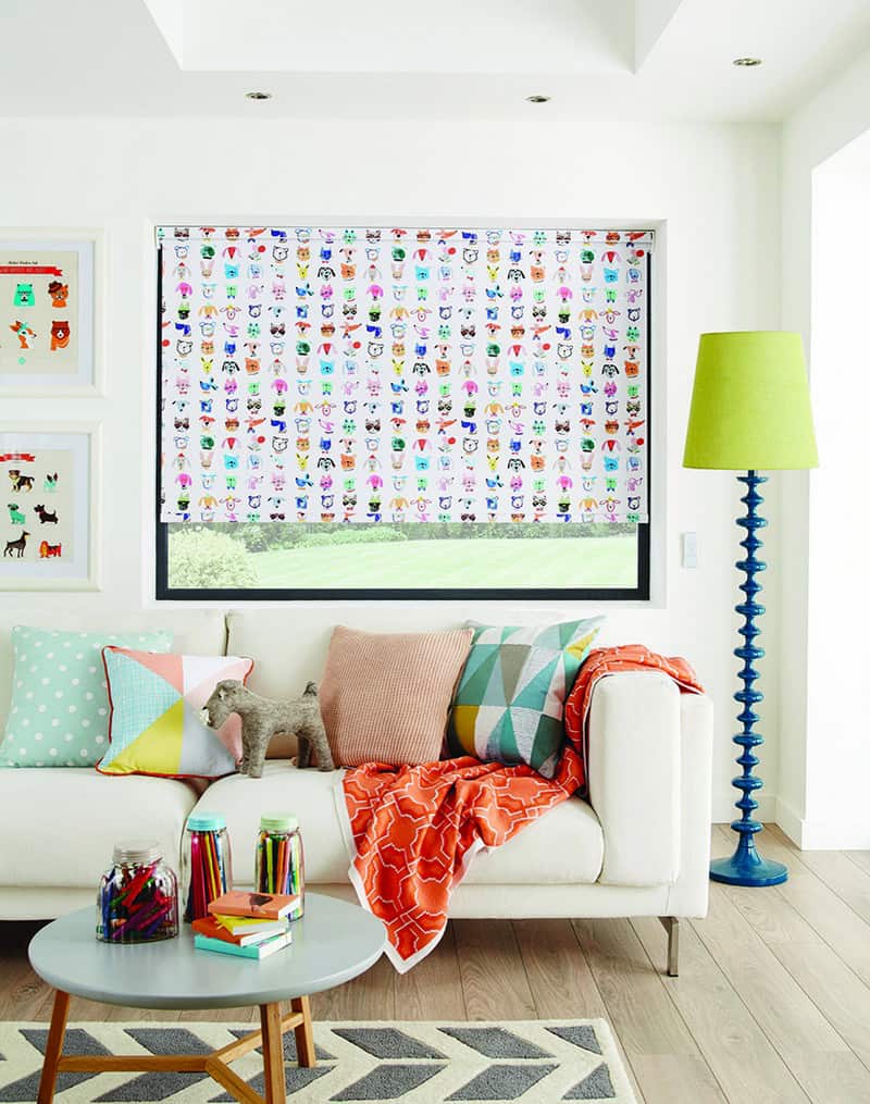 A white living room with colorful roller blinds.